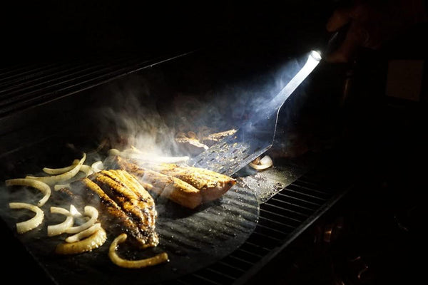 A Grillight LED Spatula being used to grill meat in the dark