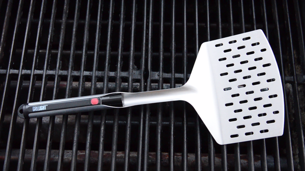 A Giant Edition Grillight LED Spatula laid on top of a grill